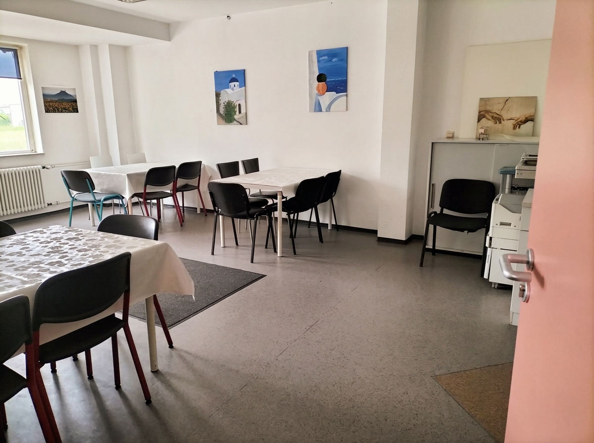 Heller Gruppenraum der Ergotherapiepraxis mit großen Fenstern, Tischen und Stühlen