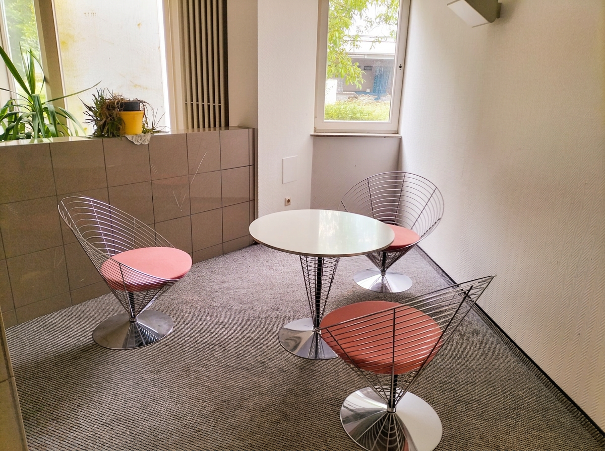 Sitzgruppe mit runden Sesseln und kleinem Tisch im Wartebereich der Ergotherapiepraxis