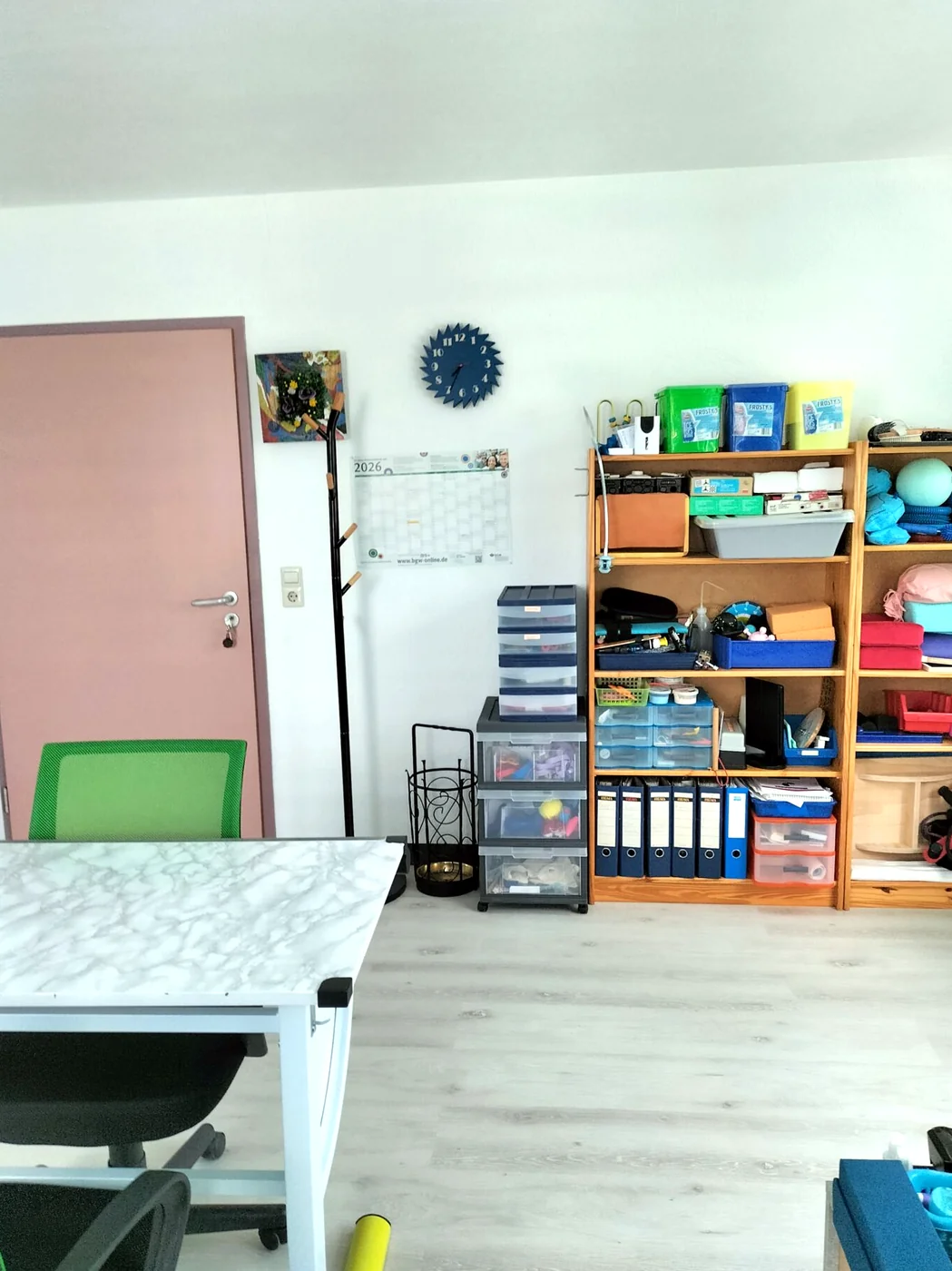 Behandlungsraum mit großem Holzregal voller Therapiematerial, Spiele und Übungsmaterial für Hand und Alltag